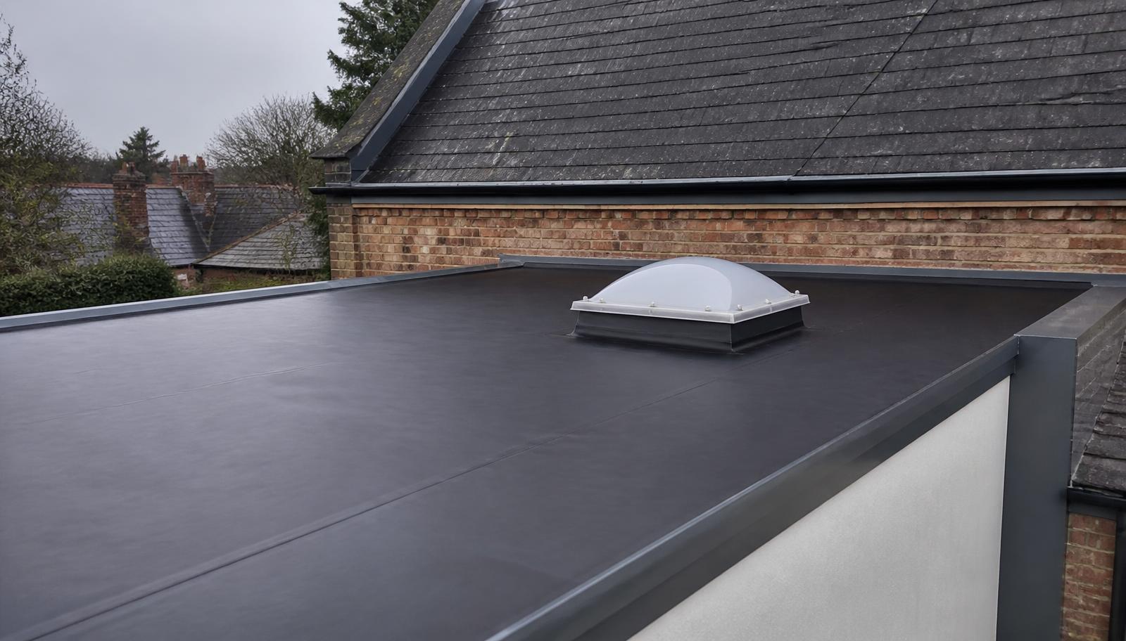 New black EPDM rubber flat roof on a British house extension with welded seams, grey trims and a domed rooflight.